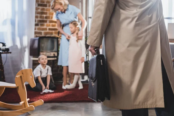 Schnappschuss eines Vaters mit Aktentasche, der nach Hause kommt und Familie im Hintergrund, Stil der 1950er Jahre — Stockfoto