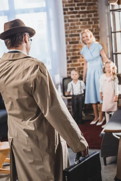 Rückseite des Vaters mit Aktentasche, der nach Hause kommt und die glückliche Familie betrachtet, 50er Jahre — Stockfoto