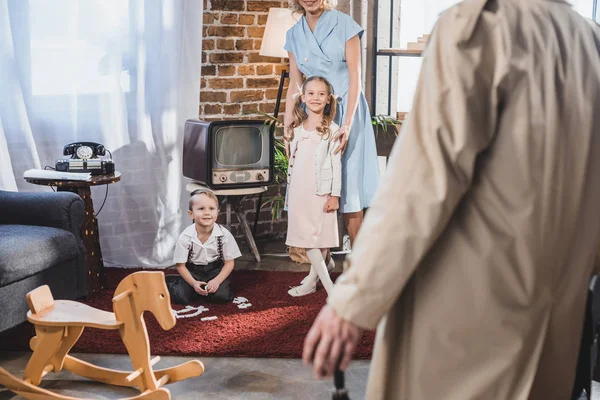 Plan recadré de père rentrant à la maison et regardant la famille heureuse jouer à la maison, style des années 1950 — Photo de stock