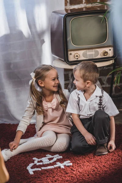 Niños pequeños y felices en la década de 1950 ropa de estilo jugando con fichas de dominó en casa — Stock Photo
