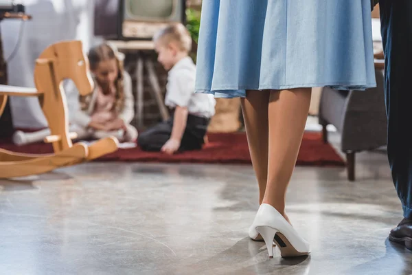 Low section of parents standing together while little kids playing at home, 1950s style — Stock Photo