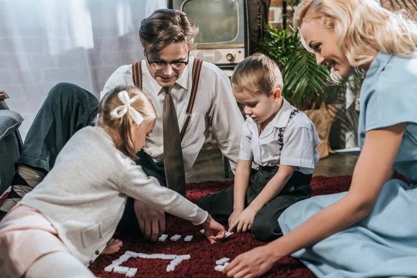 Lächelnde altmodische Familie, die zu Hause gemeinsam Dominosteine spielt — Stockfoto