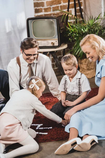 Happy 50s style family playing dominoes together at home — Stock Photo