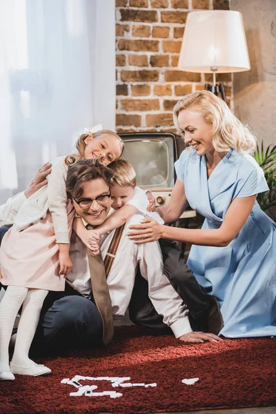 Feliz família vintage abraçando enquanto joga dominó em casa — Fotografia de Stock