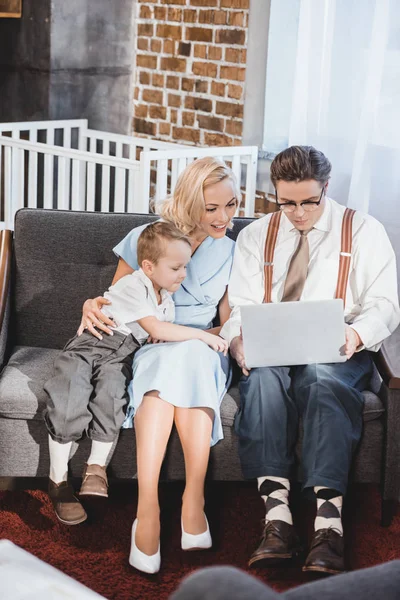 Famiglia di stile anni 50 sorridente usando il computer portatile insieme a casa — Foto stock