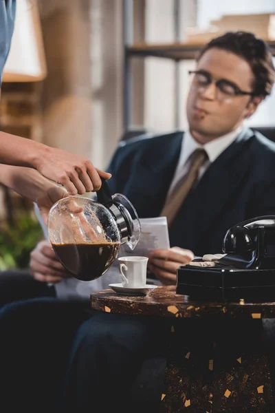 Cropped shot of woman pouring coffee to husband reading newspaper, 1950s style — Stock Photo