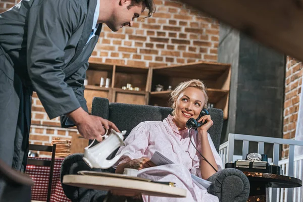 Husband pouring coffee to happy wife talking by vintage telephone — Stock Photo