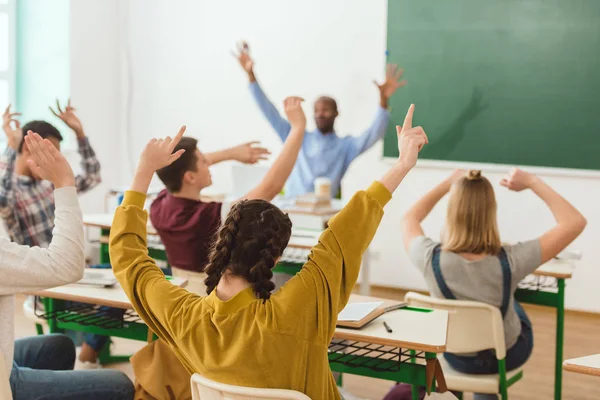 Visão traseira crianças em idade escolar e professor descansando com braços levantados — Fotografia de Stock