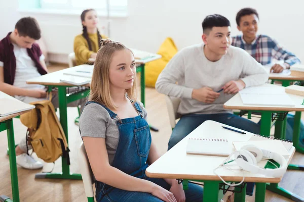 Grupo de estudiantes adolescentes multiculturales de secundaria sentados en el aula - foto de stock
