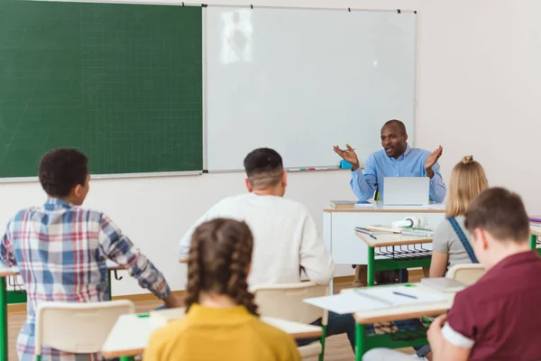 Rear view of multiethnic high school teenage students and african american teacher with wide arms — Stock Photo