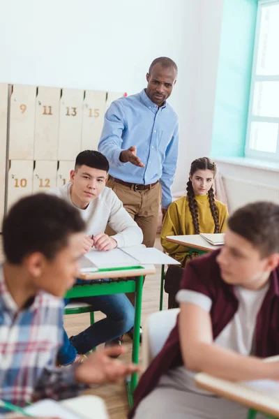 Afrikanisch-amerikanischer Lehrer zeigt während des Unterrichts auf sprechende High-School-Teenager — Stockfoto