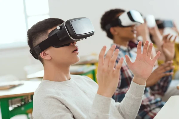 Vista lateral de estudiantes adolescentes multiculturales de secundaria usando auriculares de realidad virtual - foto de stock