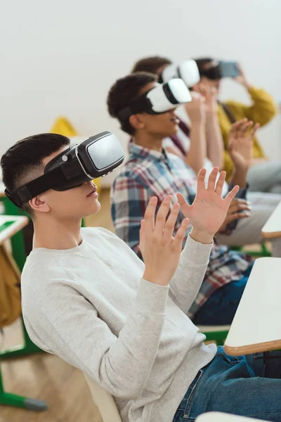 Visão lateral de escolares multiculturais usando fones de ouvido de realidade virtual — Fotografia de Stock