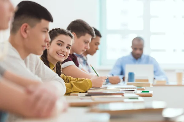 Grupo multicultural de estudiantes adolescentes de secundaria y profesor en el escritorio con computadora portátil en el aula durante la lección - foto de stock