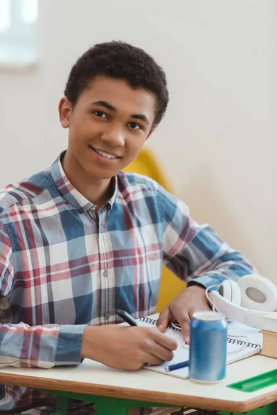 Portrait of african american high school student writing in textbook — Stock Photo