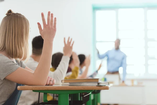 Старшеклассники поднимают руки, чтобы ответить на вопрос учителя — стоковое фото