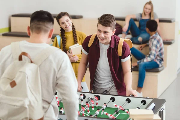 Happy high school students playing table football at school corridor — Stock Photo