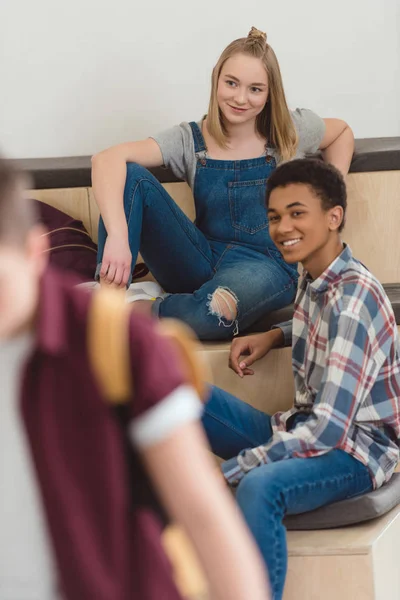 Adolescentes estudiantes pareja pasar tiempo juntos en la escuela pasillo - foto de stock