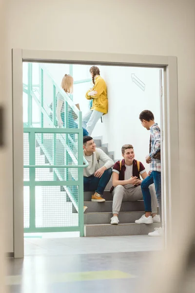Groupe d'élèves du secondaire passant du temps sur les escaliers à l'école pendant la pause — Photo de stock