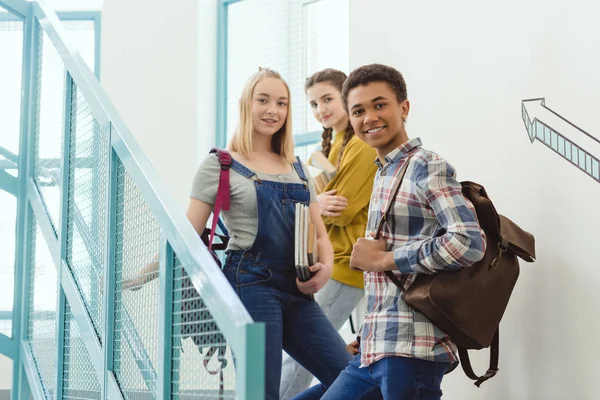 Gymnasiasten stehen in der Schule auf Treppen und schauen in die Kamera — Stockfoto