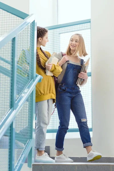 Teenage schoolgirls with backpacks and books walking on stairs — Stock Photo