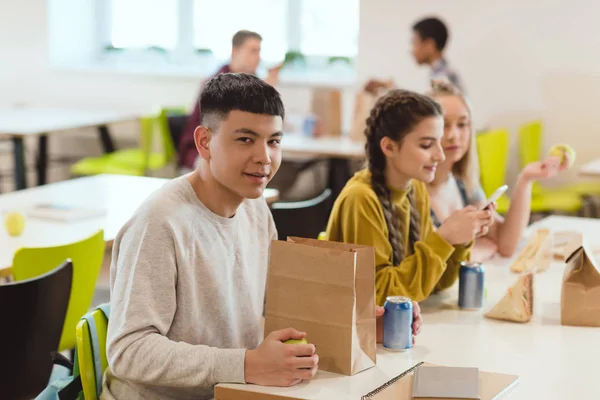 Grupo multiétnico de estudiantes de secundaria en la cafetería de la escuela - foto de stock