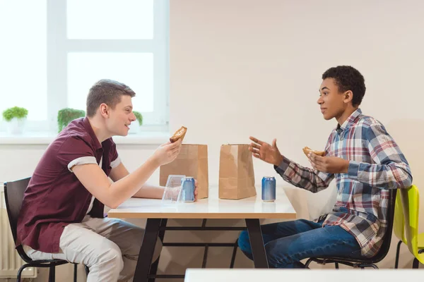 Подростки разговаривают в школьной столовой во время обеда — стоковое фото