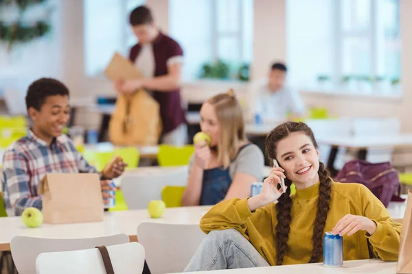 Happy teen schoolgirl talking by phone at school cafeteria — Stock Photo
