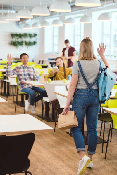 Happy high school students greeting their classmate at school cafeteria — Stock Photo