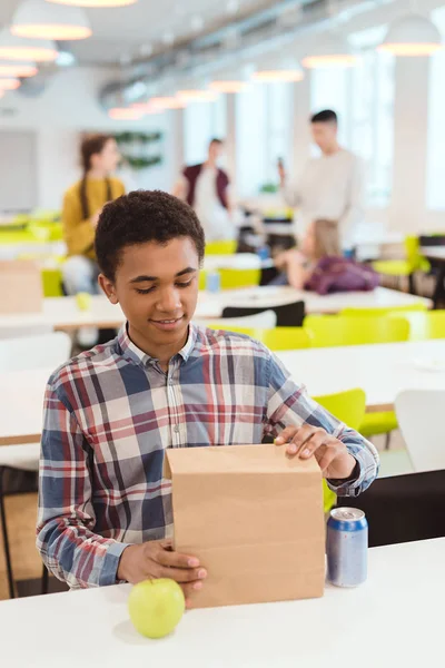 Afrikanisch-amerikanischer Schüler öffnet Mittagssack in der Schulmensa — Stockfoto