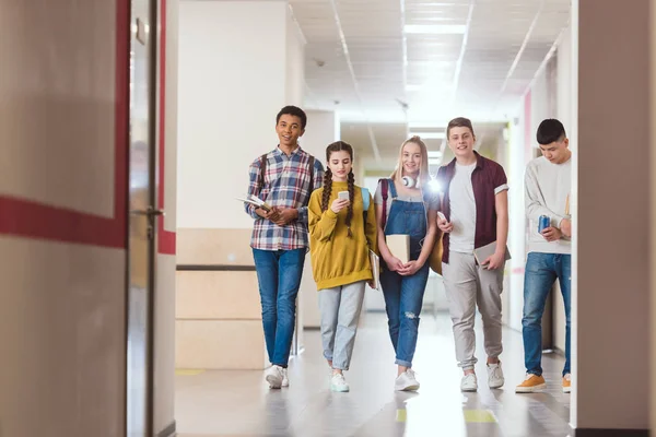 Gruppo di compagni di classe del liceo che camminano lungo il corridoio scolastico — Foto stock