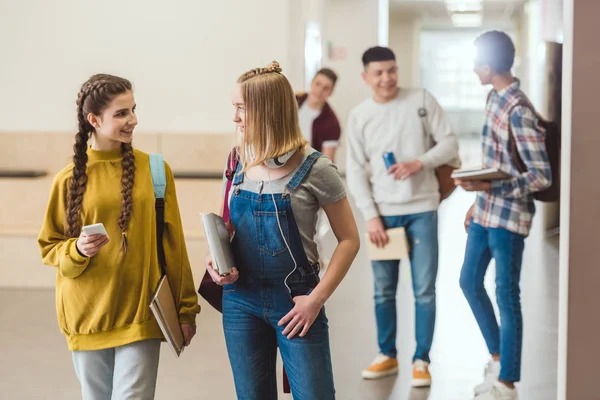 Compañeros de clase de secundaria caminando por el pasillo de la escuela juntos - foto de stock