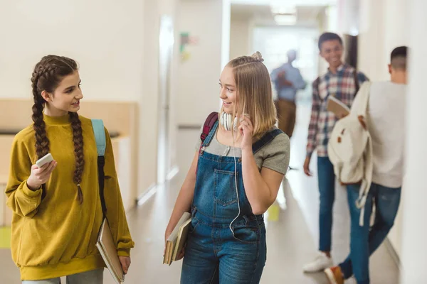 Adolescentes colegialas caminando por el pasillo de la escuela juntos y charlando — Stock Photo
