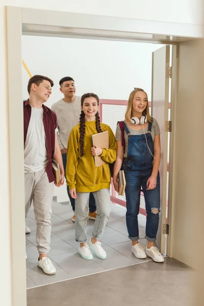 Felici studenti delle scuole superiori adolescenti che camminano lungo il corridoio scolastico — Foto stock