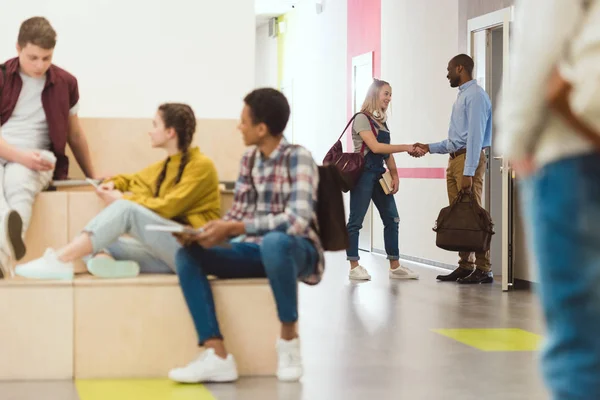 Groupe multiethnique d'élèves du secondaire passant du temps dans le corridor scolaire pendant la pause — Photo de stock