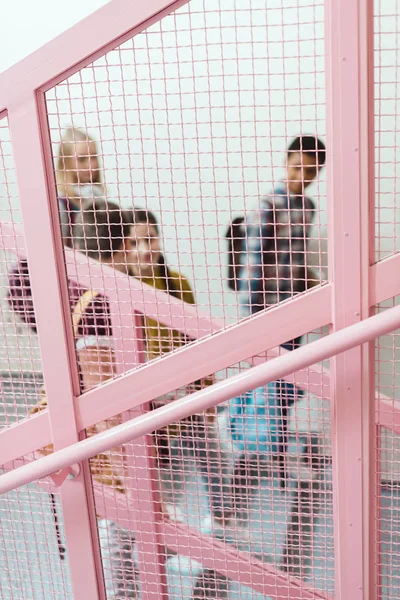 Vue à travers la grille sur le groupe d'élèves du secondaire sur les escaliers du couloir scolaire — Photo de stock