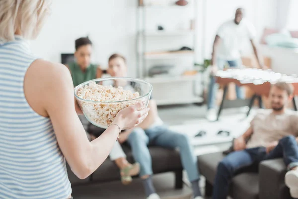 Cropped image of woman with bowl of popcorn and her friends behind — Stock Photo