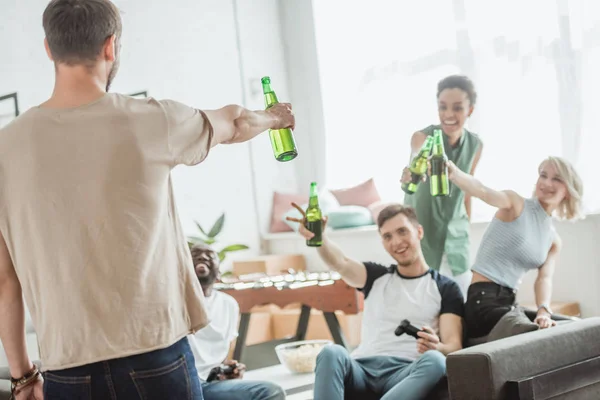 Rear view of young man with bottle of beers cheering with friend — Stock Photo