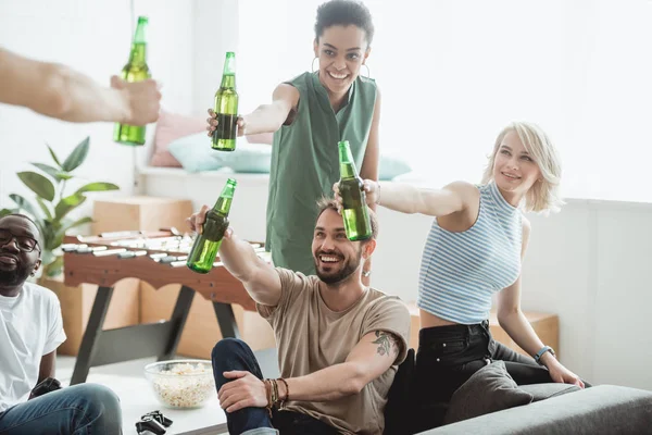 Lächelnde multikulturelle Freunde jubeln mit Bierflaschen — Stockfoto