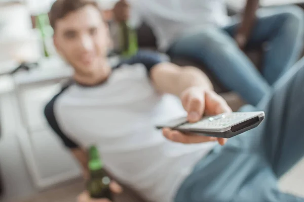 Gros plan de télécommande en main de l'homme assis avec bouteille de bière — Photo de stock