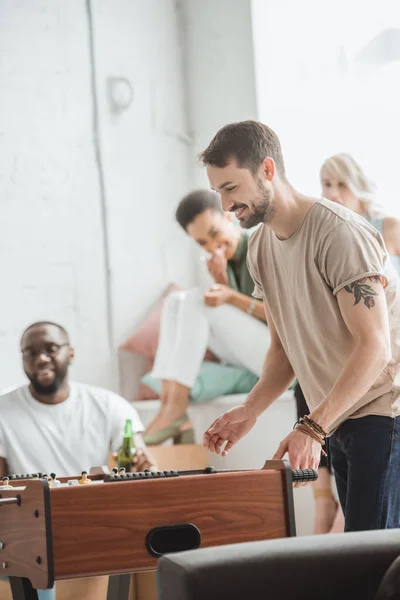 Lächelnder Mann spielt Tischfußball, während Freunde zuschauen — Stockfoto