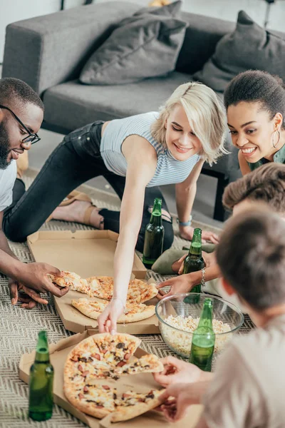 High angle view of smiling multicultural people eating pizza and drinking beer — Stock Photo