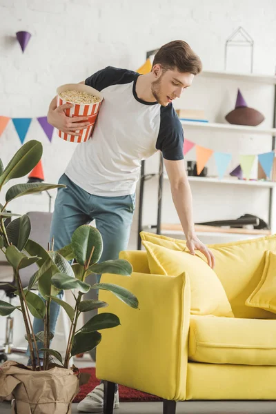 Jovem com cesta de pipoca na sala de estar decorada — Fotografia de Stock