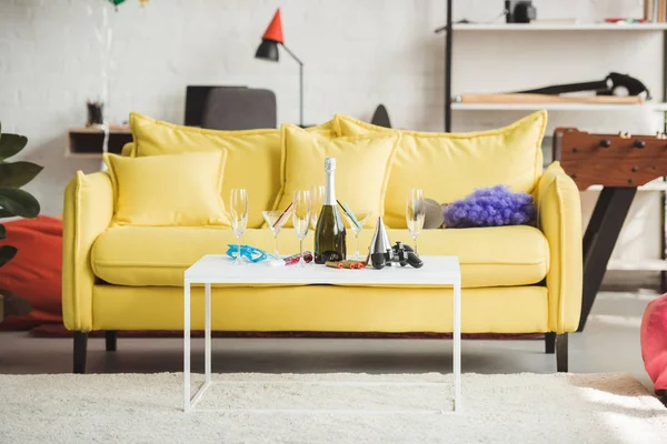 Interior of modern decorated living room with champagne bottle, glasses, joystick and party supplies on table — Stock Photo