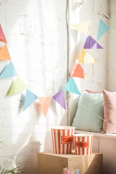 Party garland and popcorn buckets in light room — Stock Photo