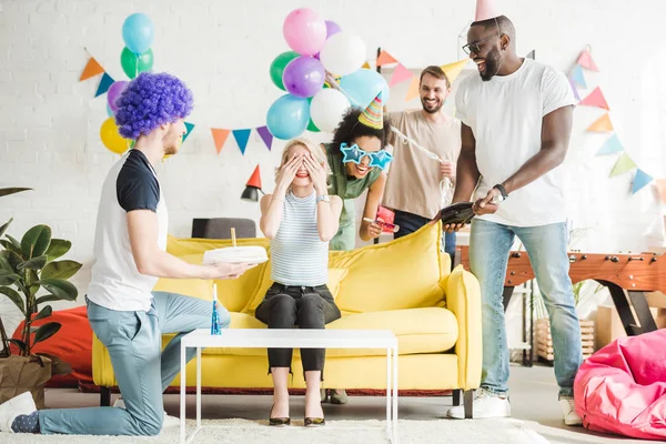 Young people greeting happy woman with birthday cake on surprise party — Stock Photo