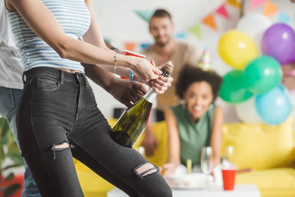Close-up view of man helping woman opening champagne at birthday party — Stock Photo