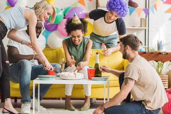 Glückliche junge Leute feiern Geburtstag mit Kuchen und Champagner — Stockfoto