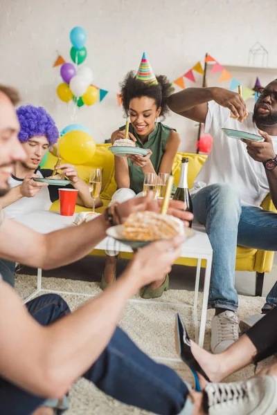 Вечірки різноманітних людей їдять торт на день народження і тримають напої — стокове фото