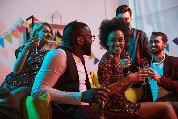 Young multiracial people celebrating with drinks in cozy room — Stock Photo